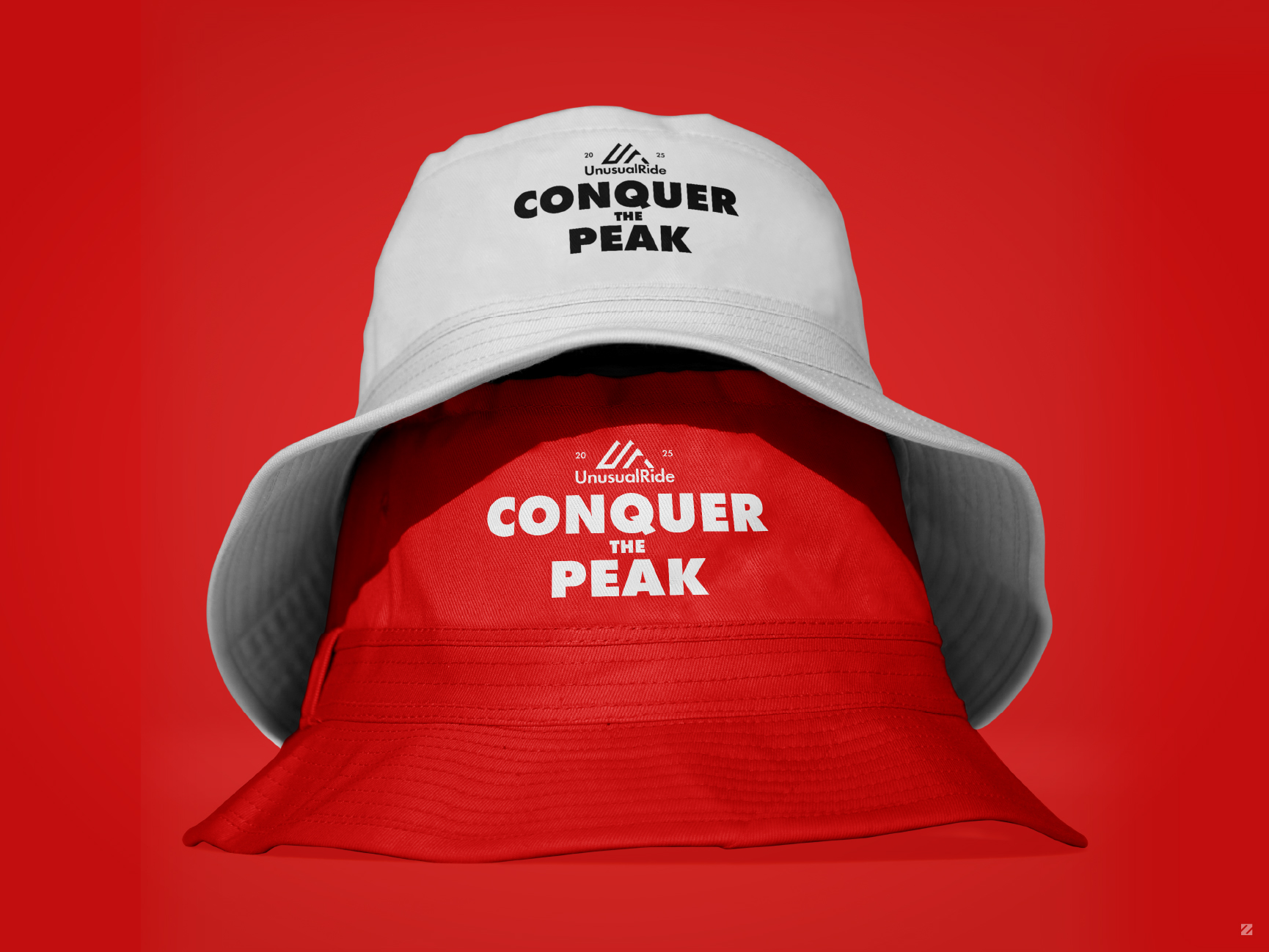 Red and white reversible bucket hat mockup with UnusualRide "Conquer the Peak" logo embroidery